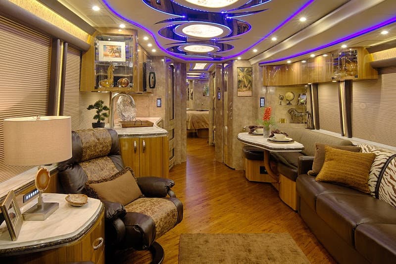 Interior of a luxury RV with blue accent lighting and comfortable seating.